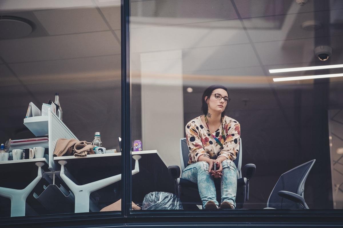 Uninspired young woman looking longingly out of an office window