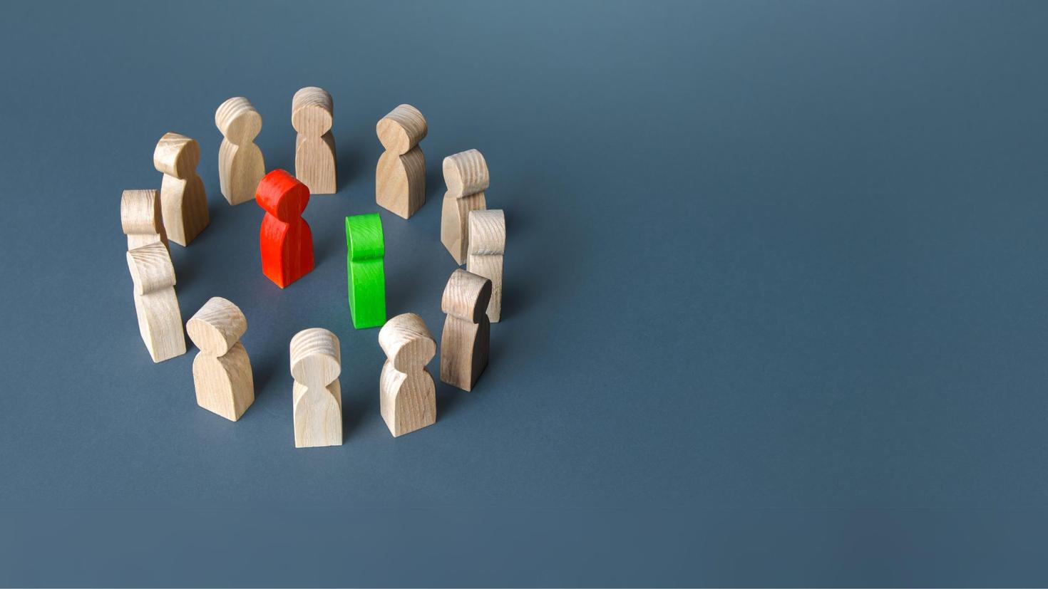 wooden figures encircling 2 opposing ones