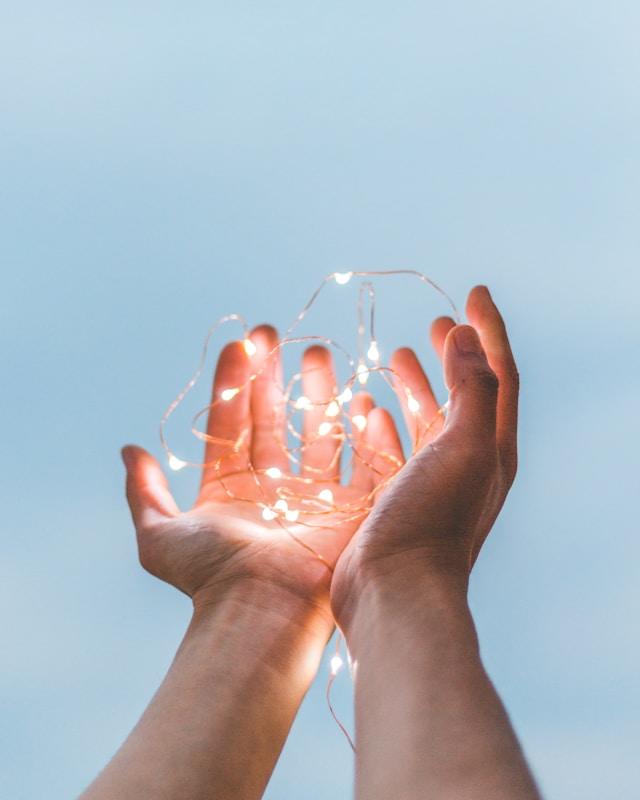 Two hands cupped holding mini lights.