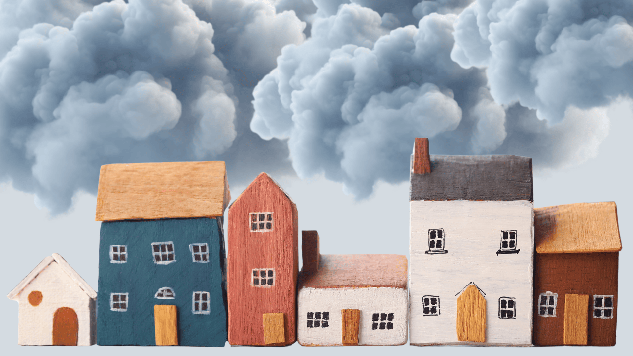 A row of small wooden houses, colourful and of varying sizes. In the background, heavy dark clouds fill the sky.