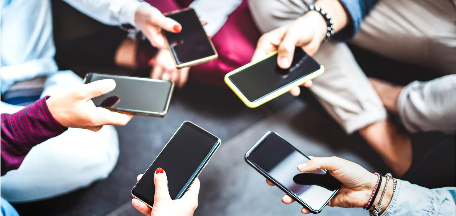 People sitting in a circle, but we only see their with hands holding smart phones with blank screens