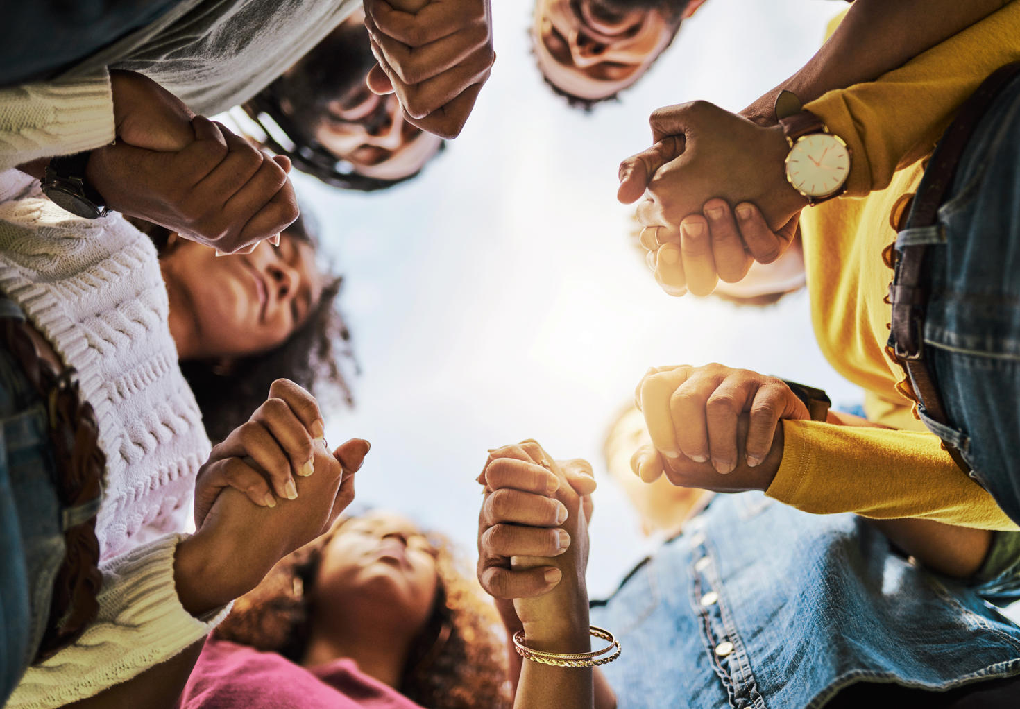 Various people holding hands seen from below