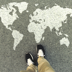 Someone's feet in black shoes in front of a world map drawn on the floor