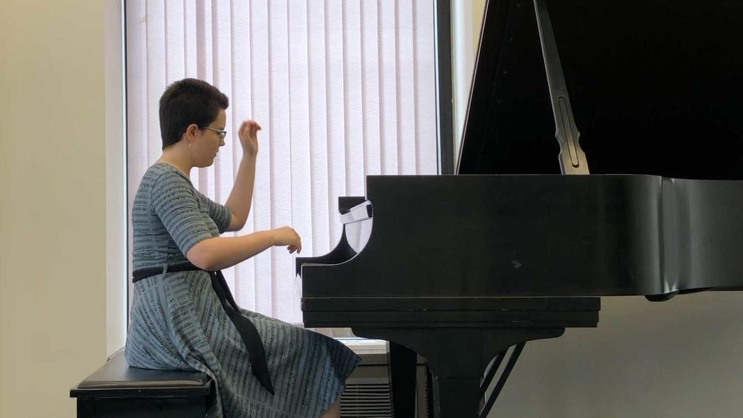 Student sitting at a piano during a recital.