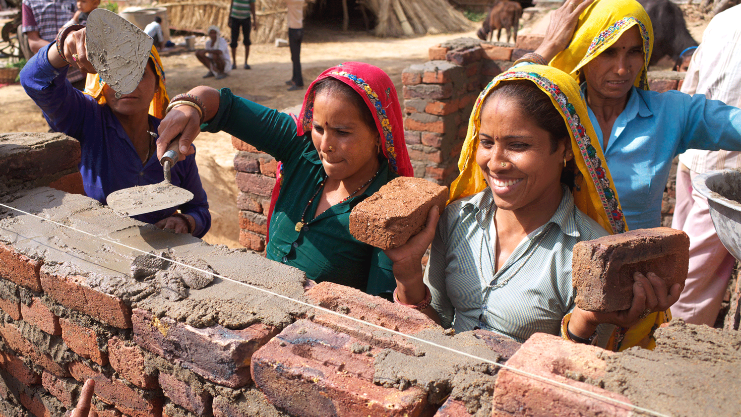 4 women working together to build a brick wall