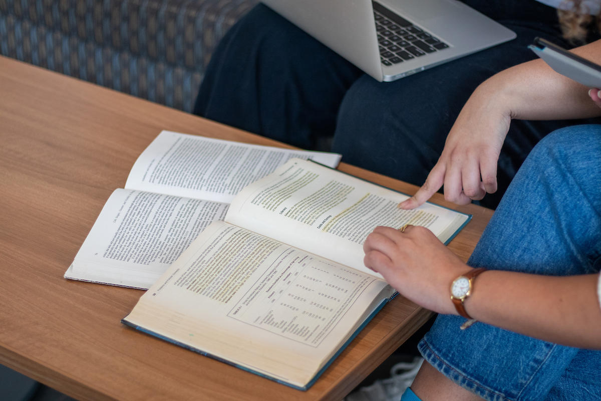 Students studying with a book and laptop