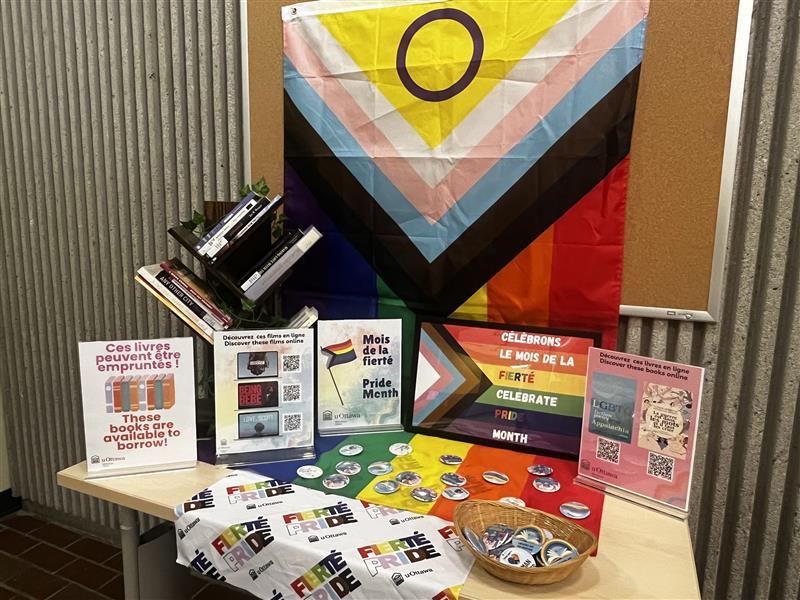 Display of books with a flag for pride month