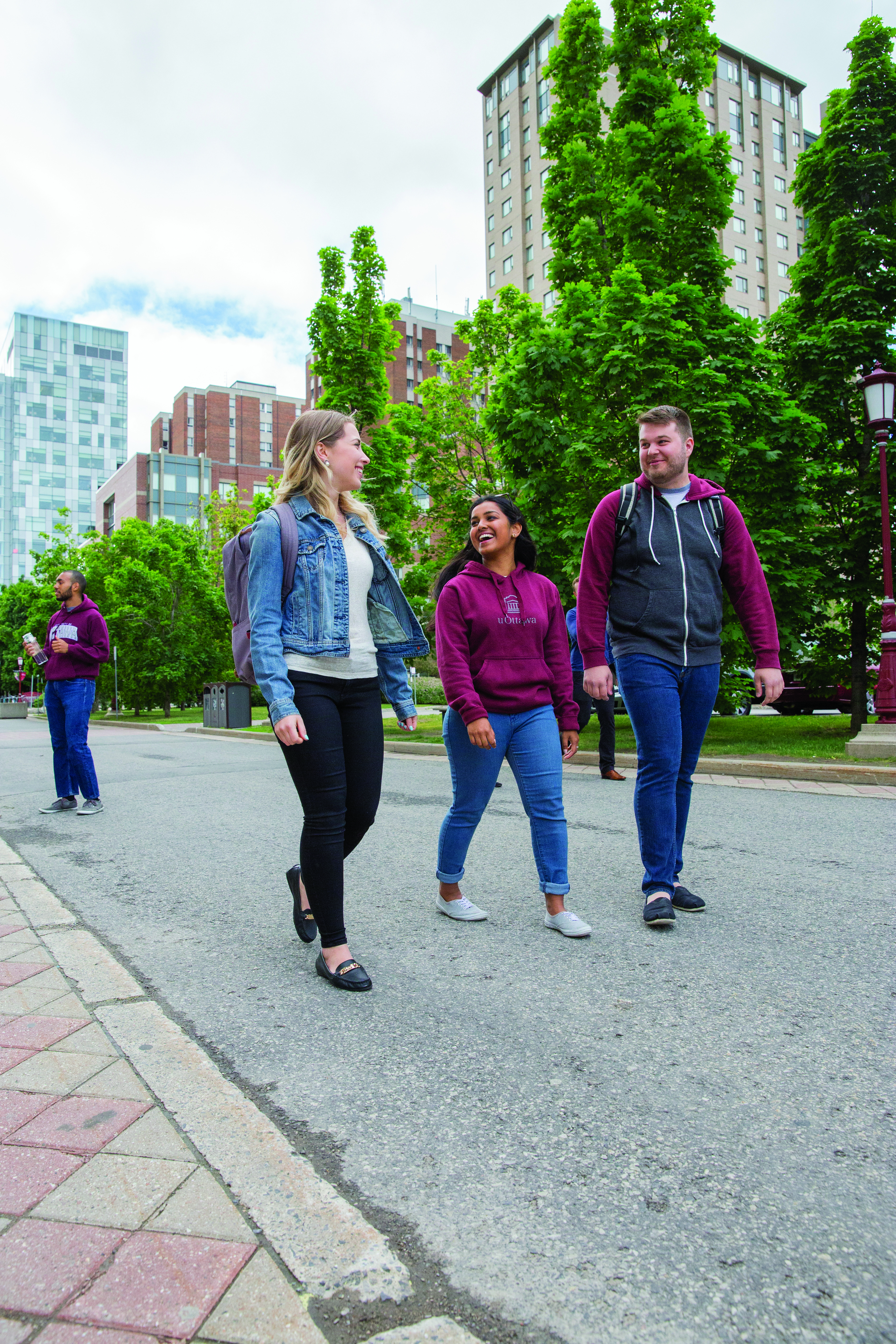 trois étudiants marchant sur l'allée centrale du campus