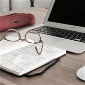 Mac book computer and an agenda on a desk