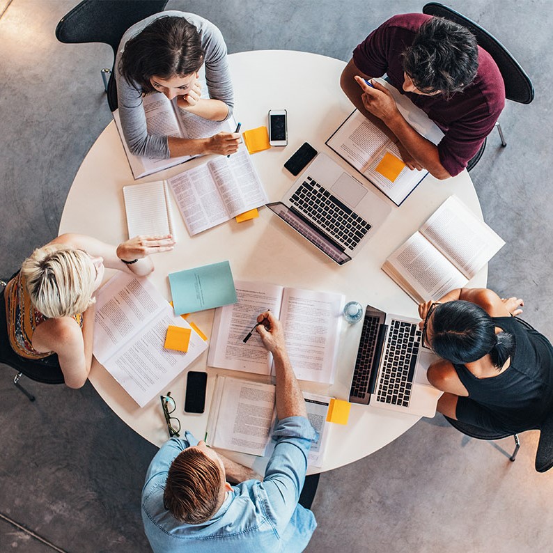 Des étudiants sont assis à une table ronde et étudient.