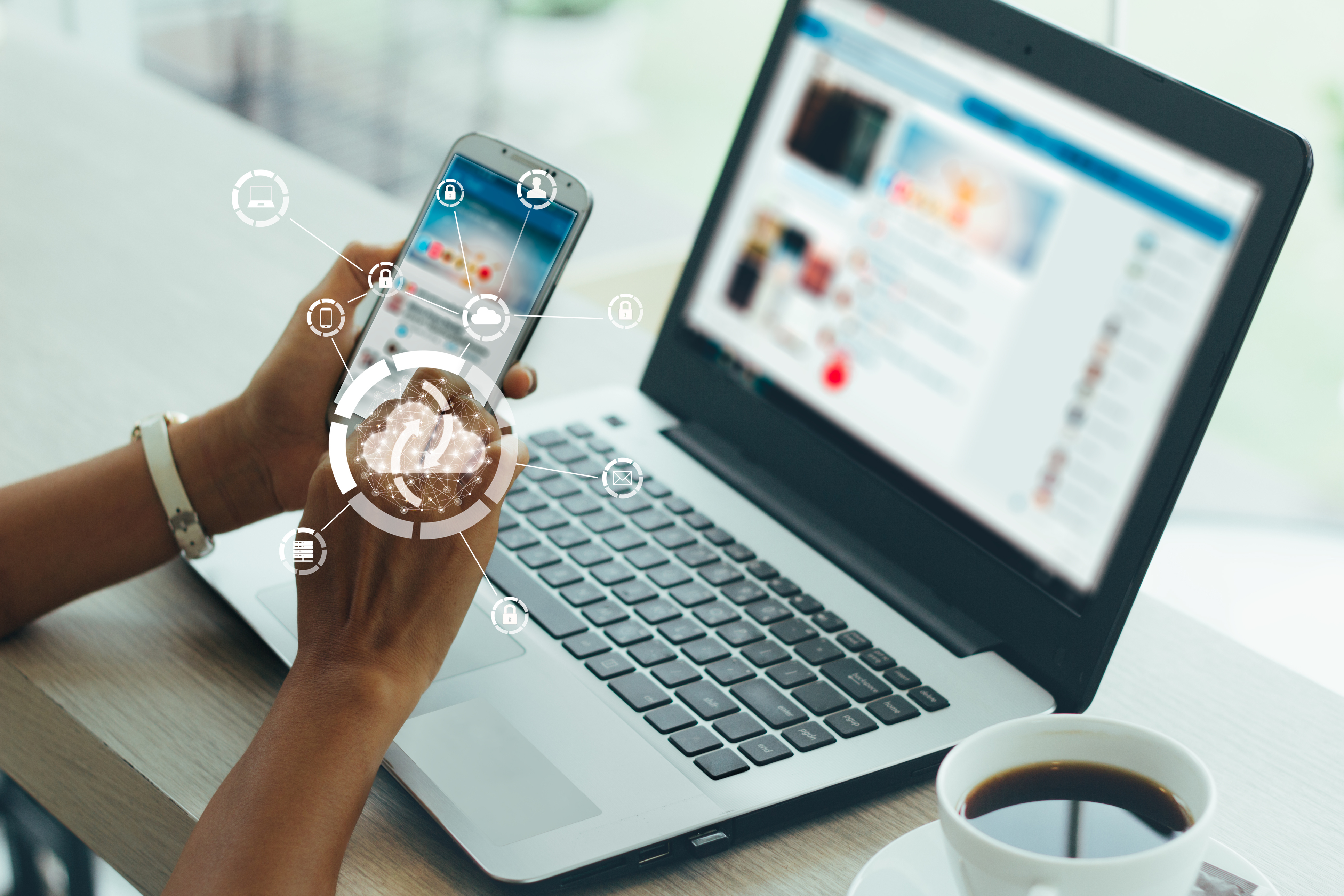 une personne travaillant sur son téléphone en face de son ordinateur.