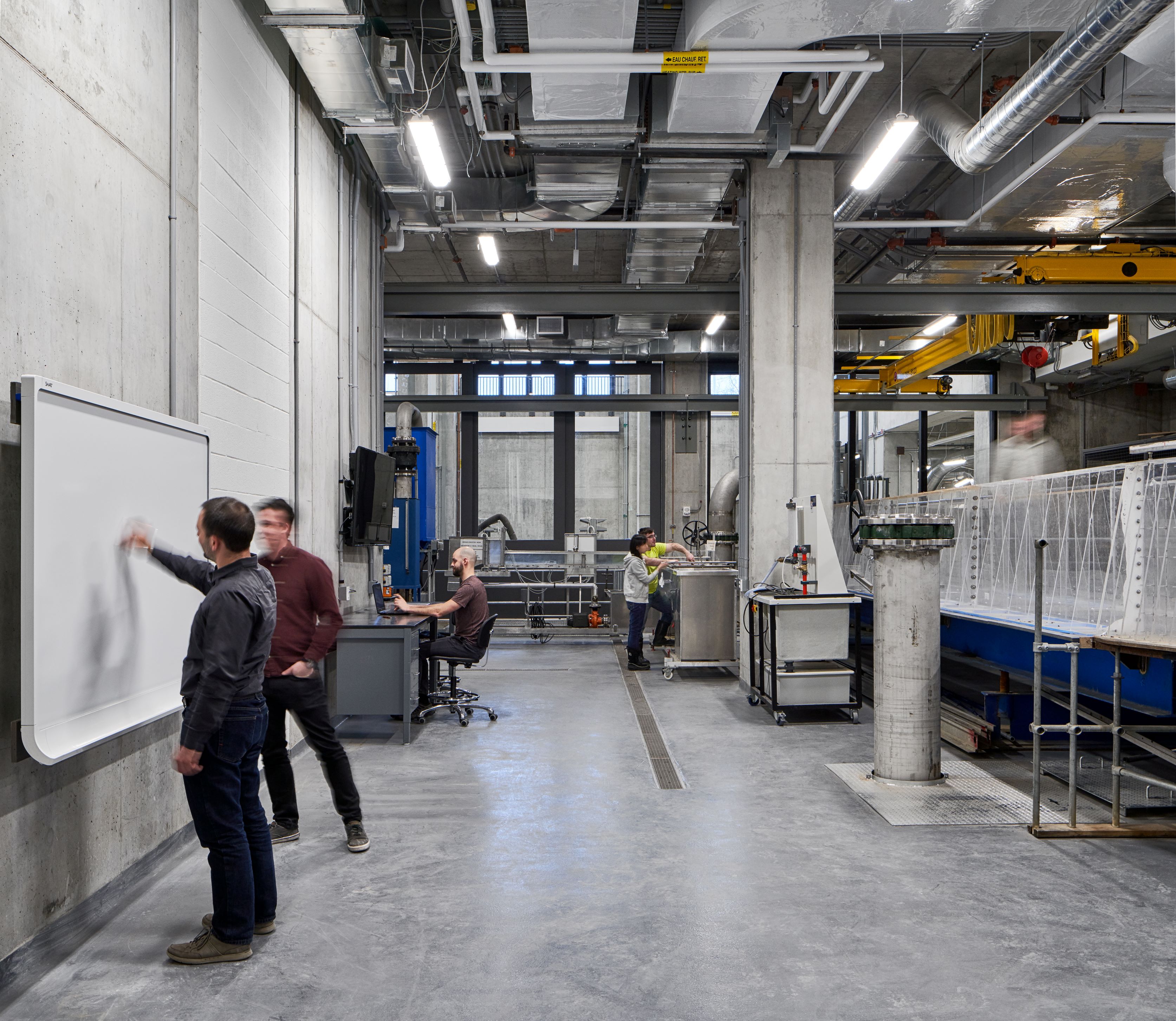 People working at different stations in an engineering workspace