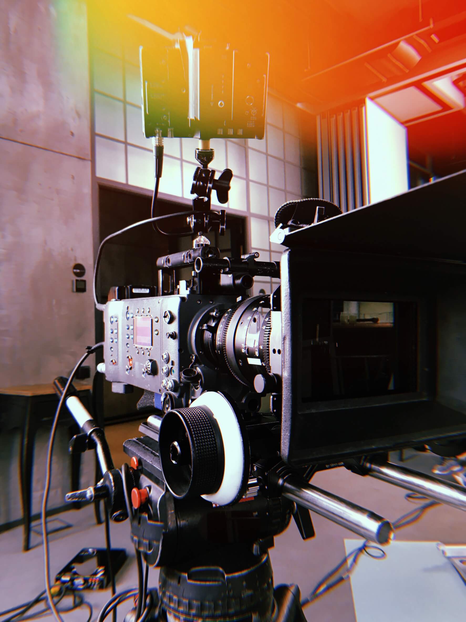 Une caméra de cinéma numérique professionnelle sur un trépied avec un matte box et un moniteur dans un studio