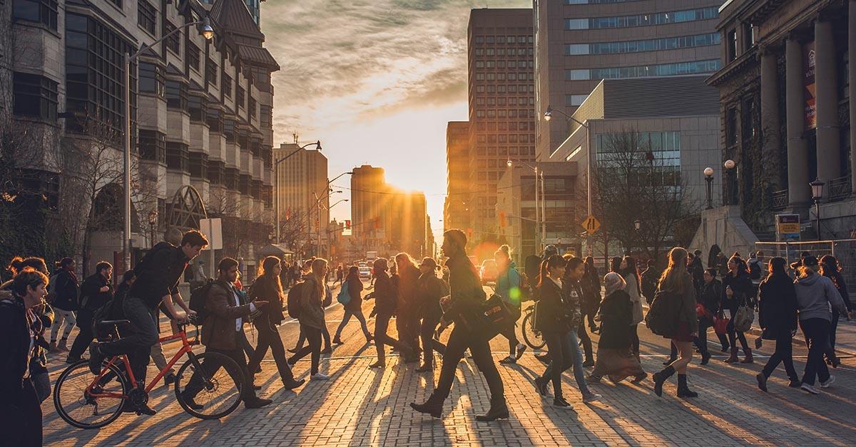 Des personnes marchant sur le campus alors que le soleil se couche derrière elles