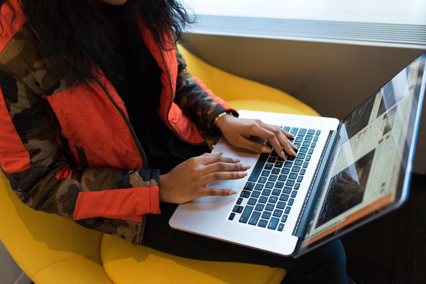 Student sits with laptop on lap