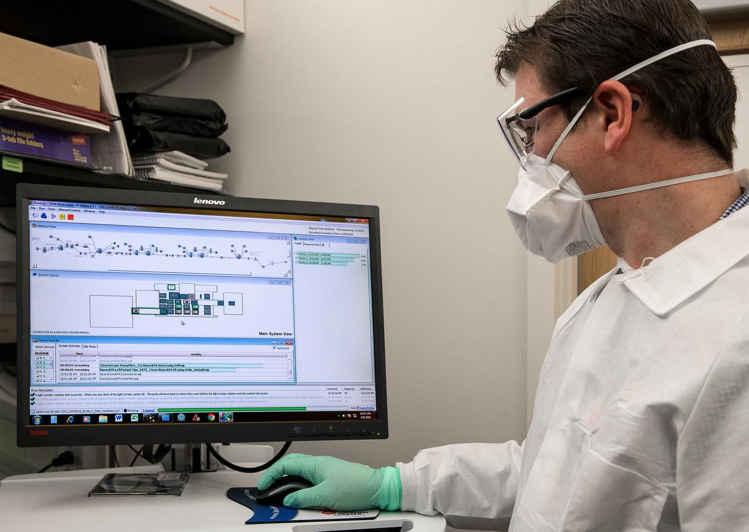 Man wearing mask and gloves works at computer 