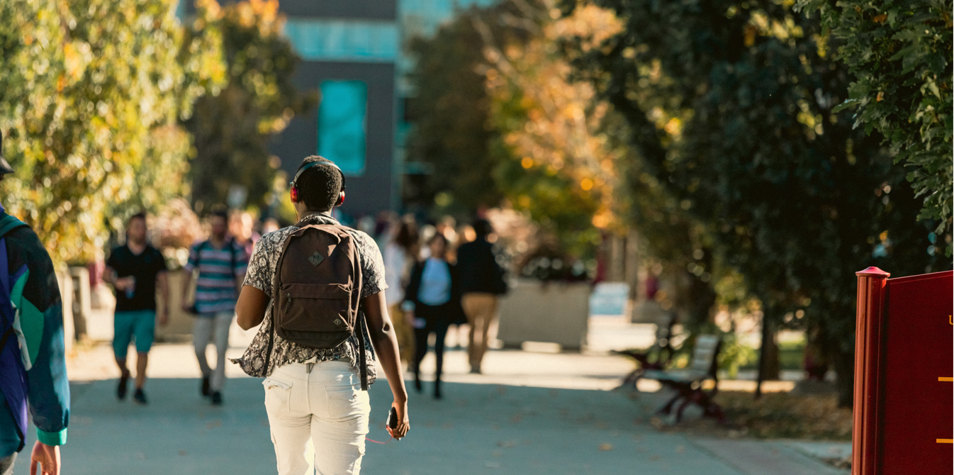 Étudiant traversant le campus avec des écouteurs.