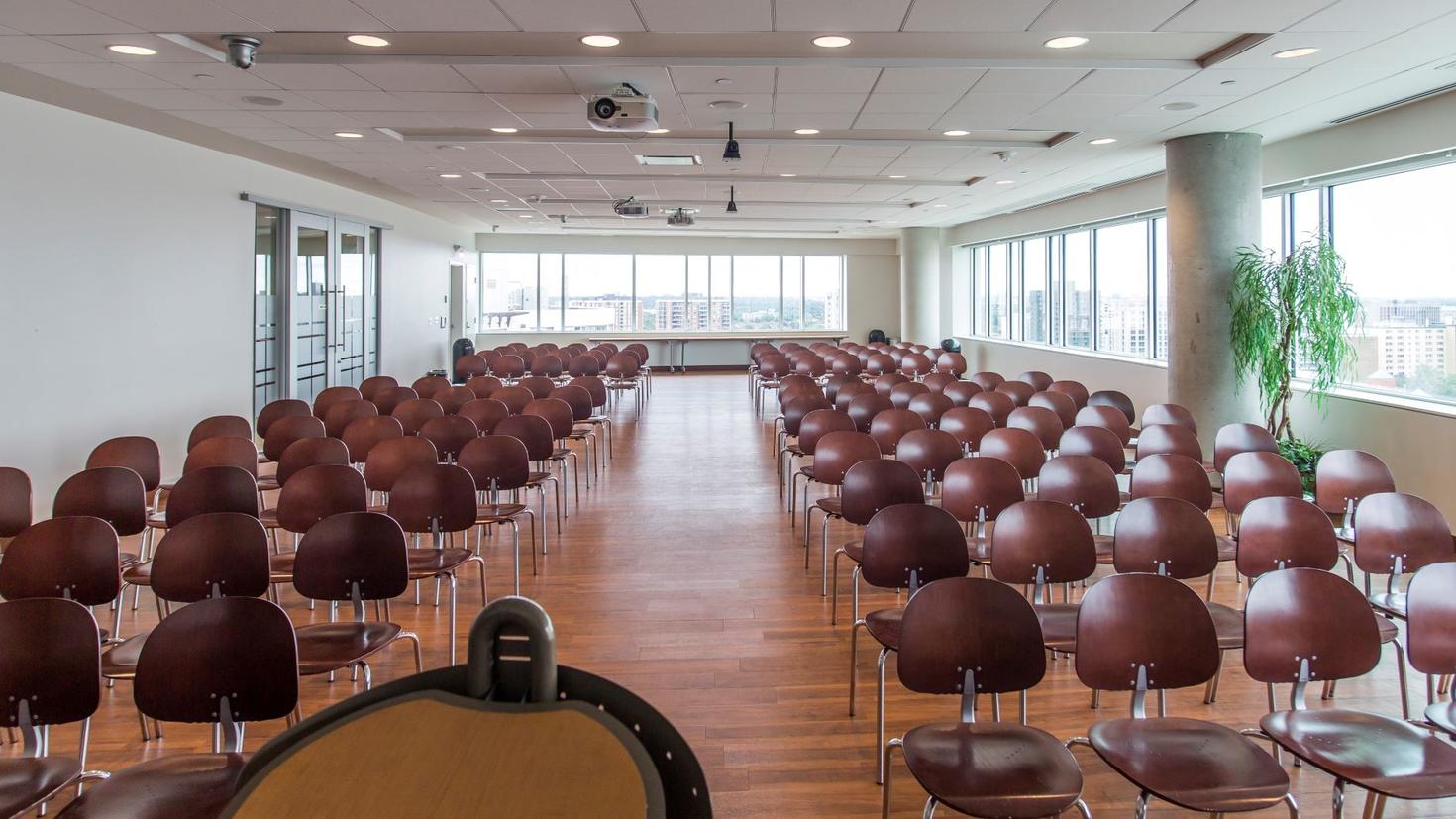 Vue de la salle remplie de chaises, derrière le podium.