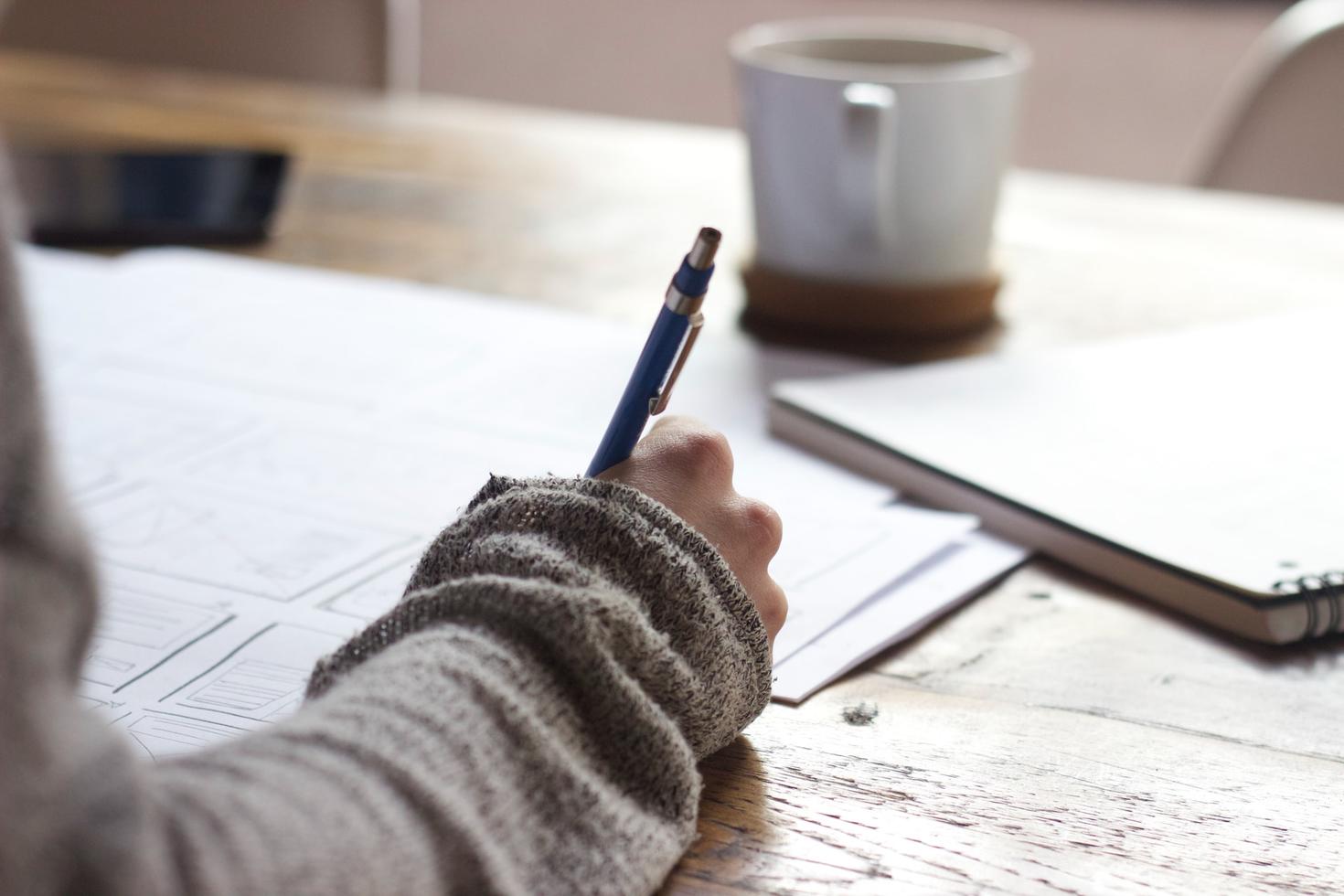 une main qui tient un stylo pour écrire dans un cahier de notes
