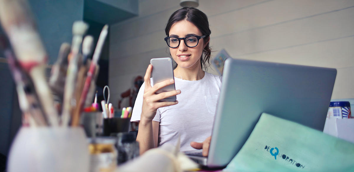 Personne regardant un téléphone portable et avec un ordinateur portable assis à une table