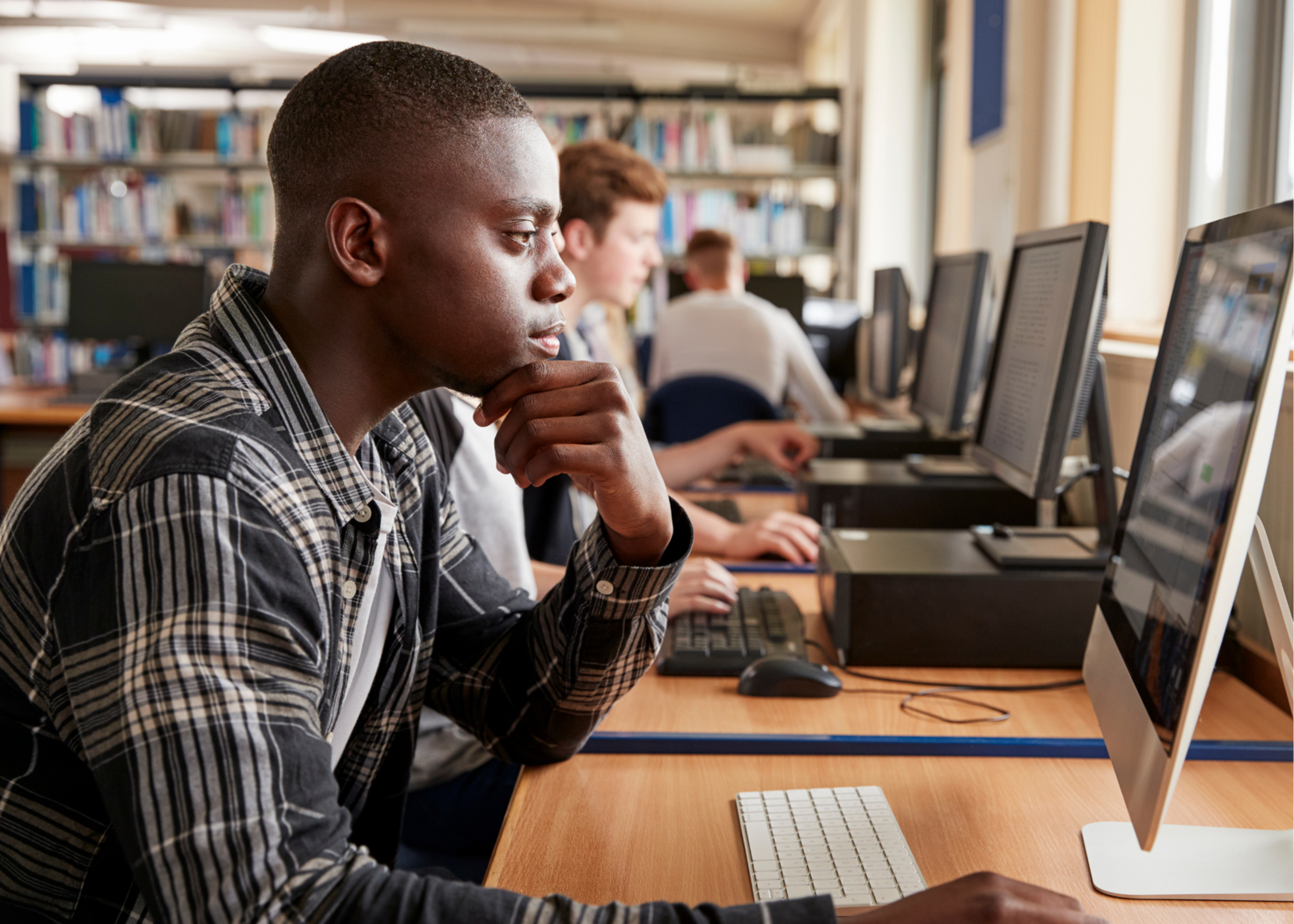 Un étudiant réfléchit en regardant son ordinateur.