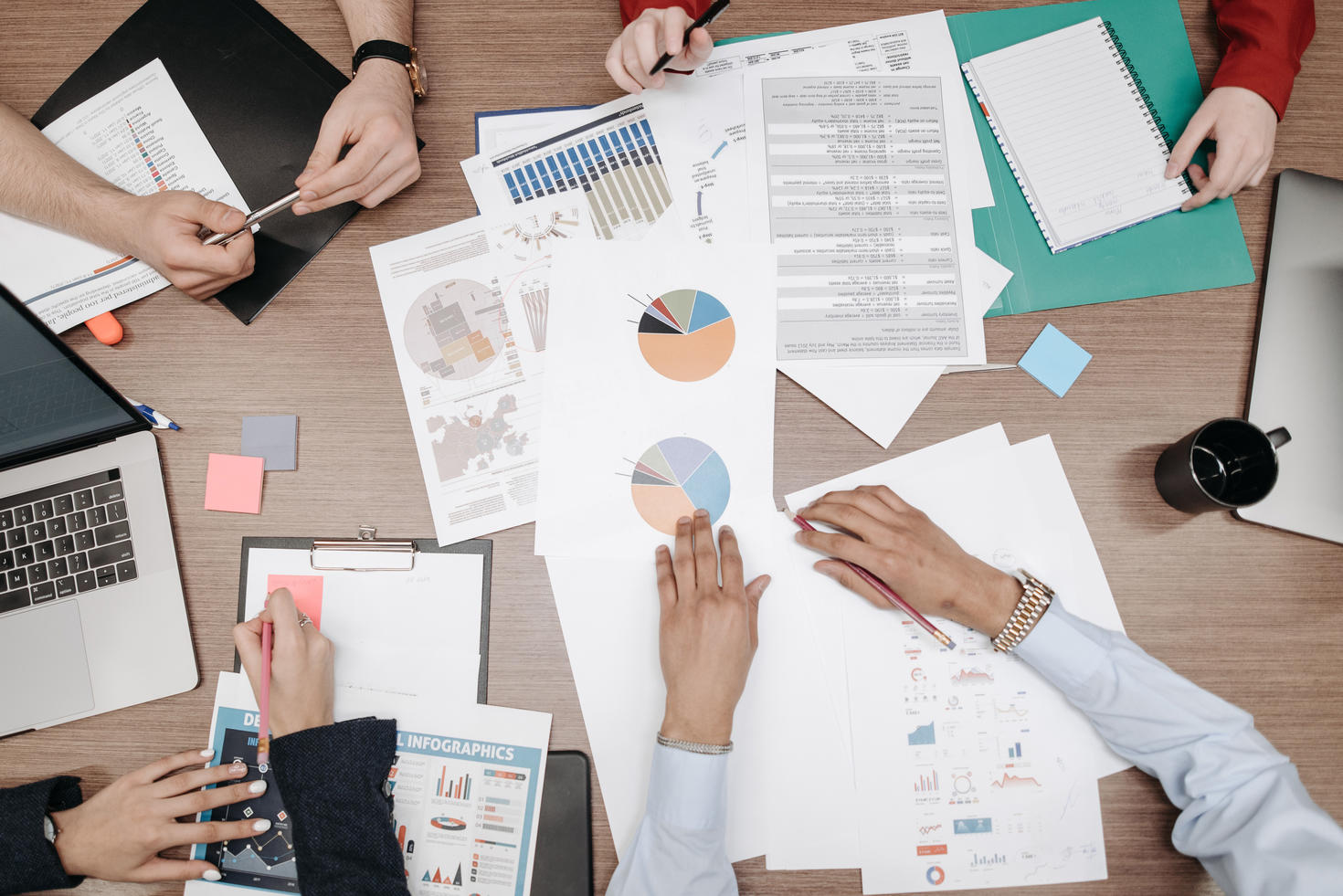 Des piles de papiers et de tableaux sur la table de travail collaborative.