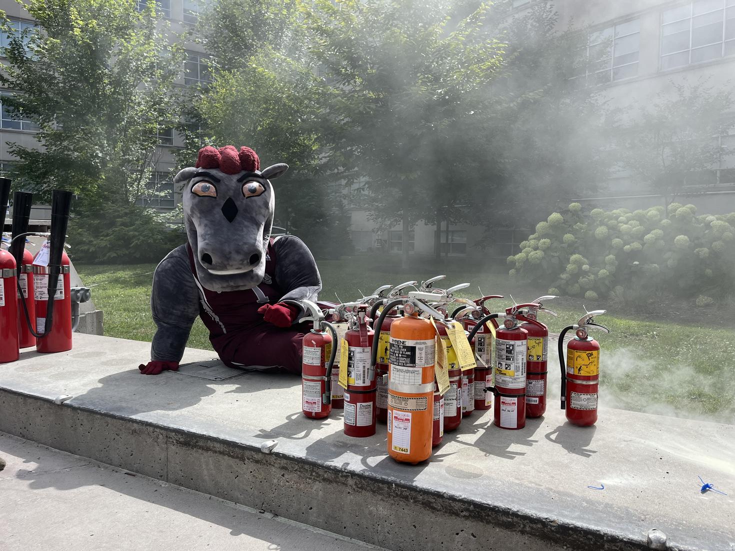 La mascotte des Gee-gees posant à côté d'extincteurs. 