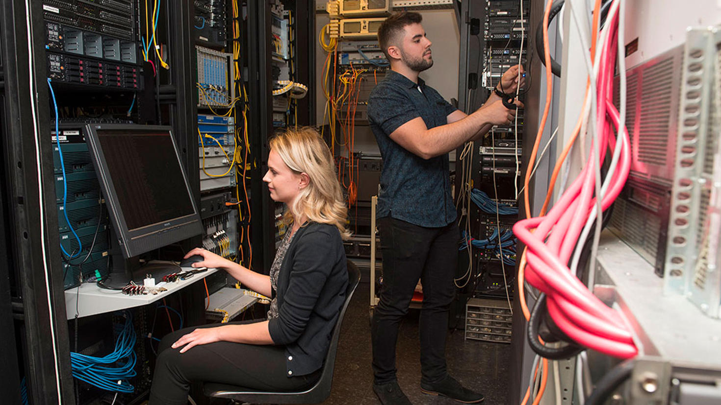 Un homme et une femme travaillent dans une salle de serveurs.
