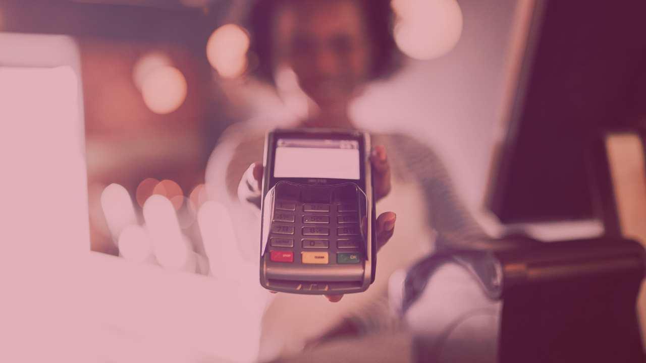 Woman behind a counter presenting an electronic payment terminal 