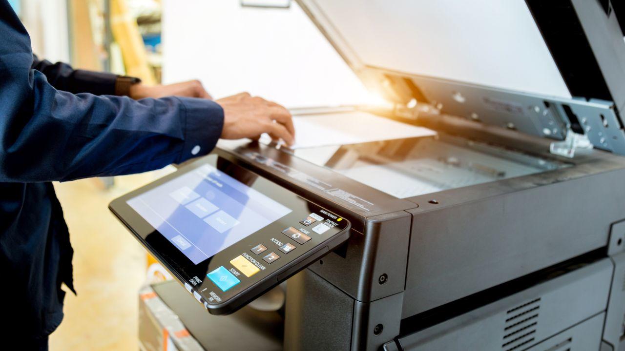 image montrant un homme qui utilise une imprimante de bureau en y mettant une feuille afin d'en faire une copie