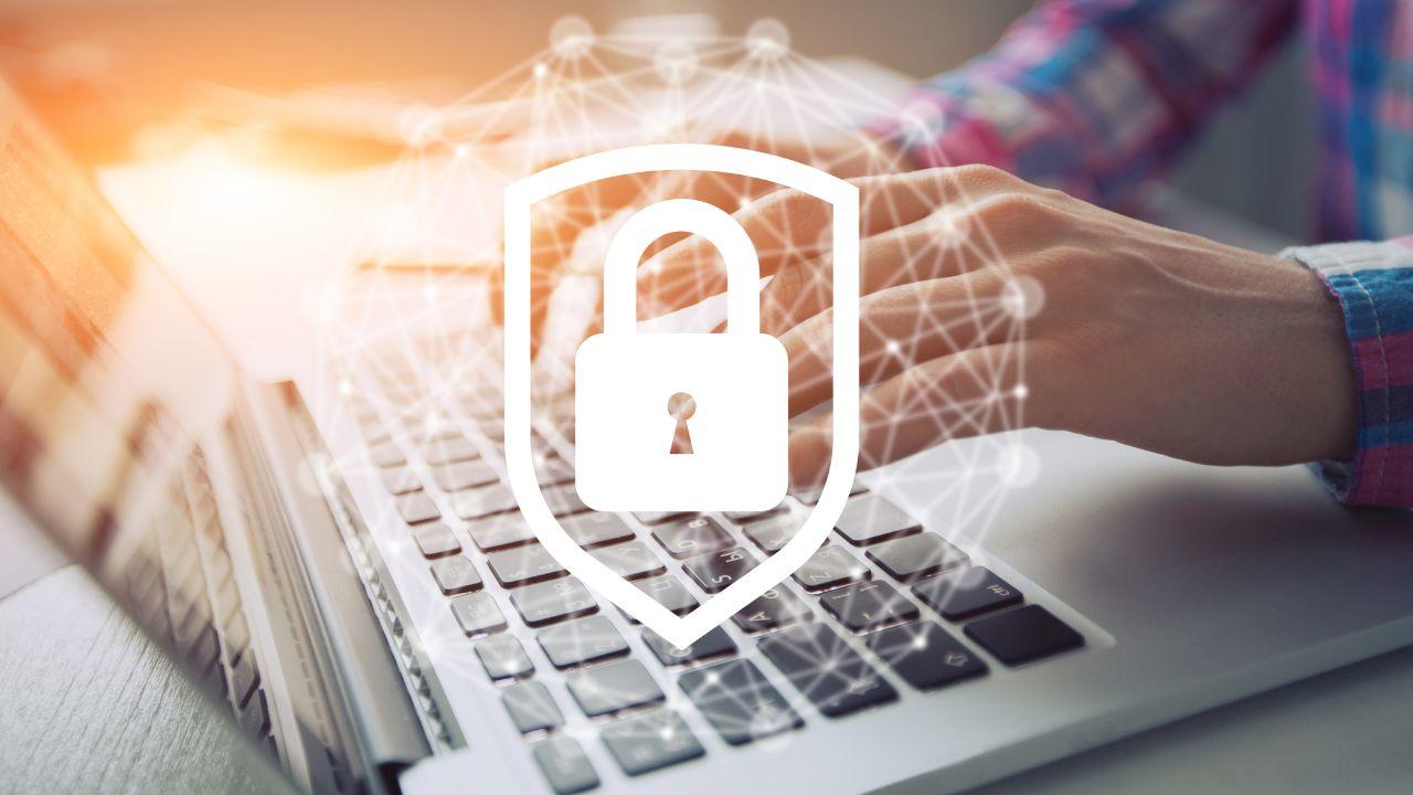 Mains d'un homme écrivant sur un clavier d'ordinateur portable en fond plus le symbole de cadenas en blanc mis en avant 