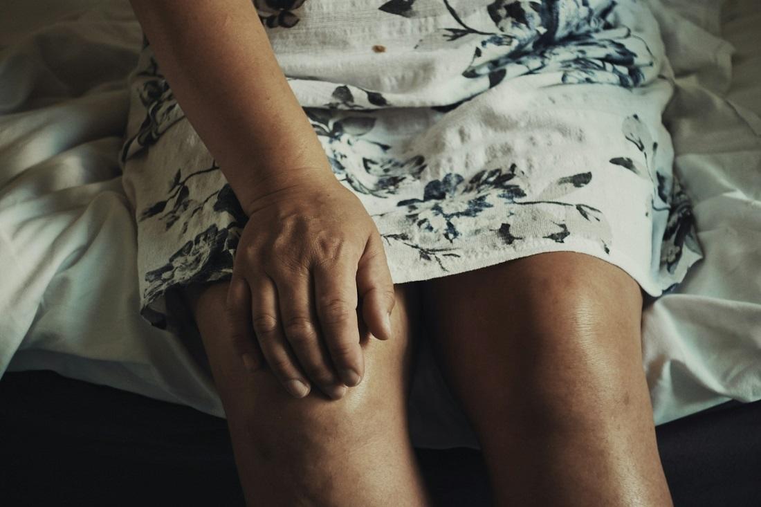 La main d'une femme agrippée à son genou en proie à une douleur probable