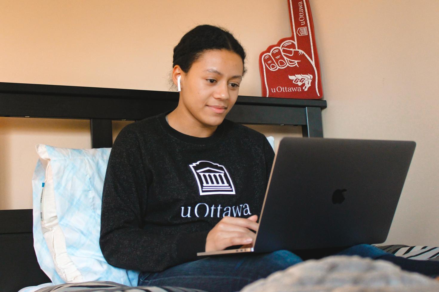 Photo d'une étudiante sur son lit avec son ordinateur portable