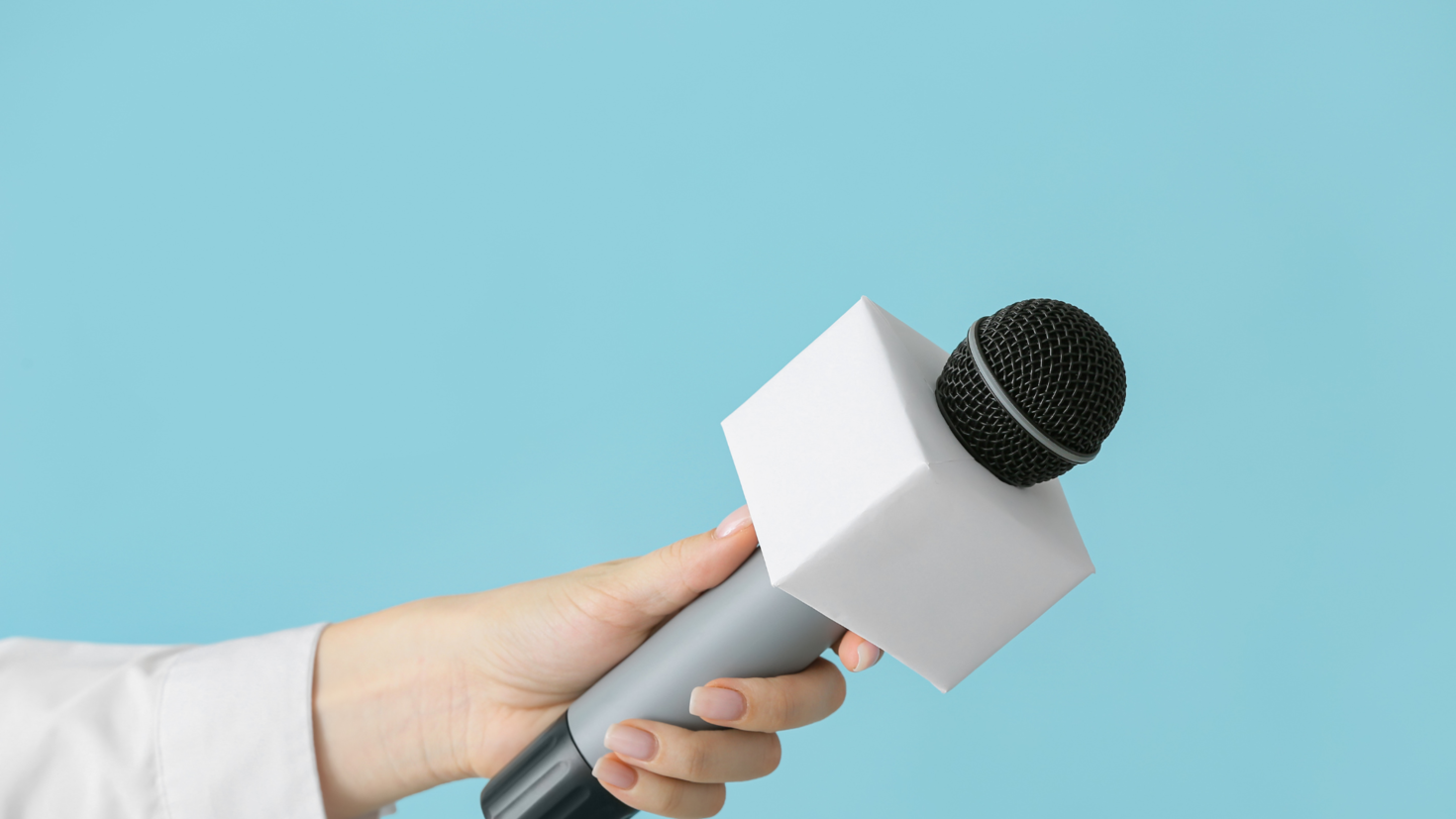 hand holding a microphone on a blue background