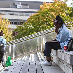 Un étudiant assis sur des marches en train d'étudier