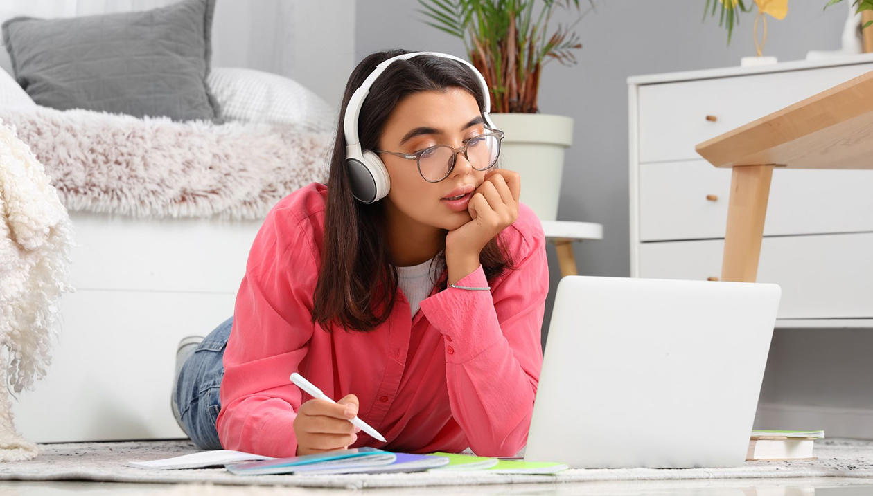 Une jeune fille regardant son ordinateur portable, un casque sur les oreilles