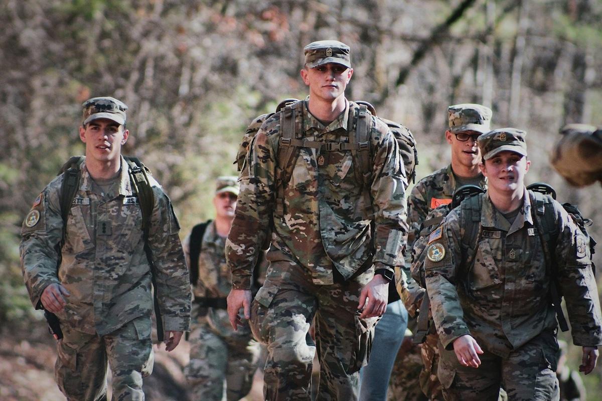 Des hommes en uniforme de camouflage debout dans un champ, en plein jour
