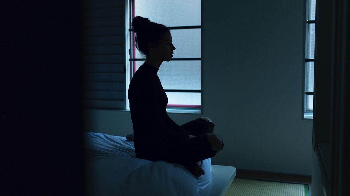 Une femme assise sur son lit dans l'obscurité
