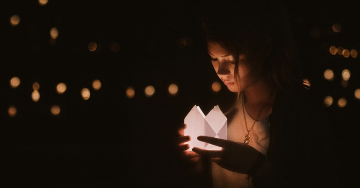 Une femme tenant une chandelle lors d'une cérémonie commémorative.