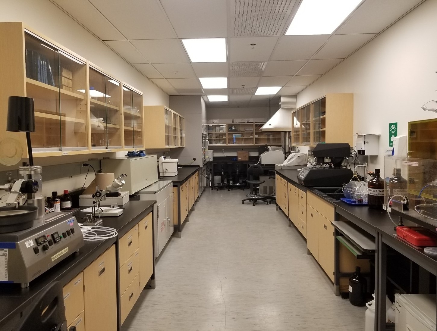 Des tables de laboratoire le long de deux murs avec de nombreux outils de laboratoires sur les tables avec des cabinets au-dessus