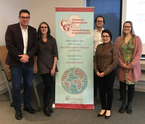 Five people standing in front of a Centre on Governance poster at a conference event