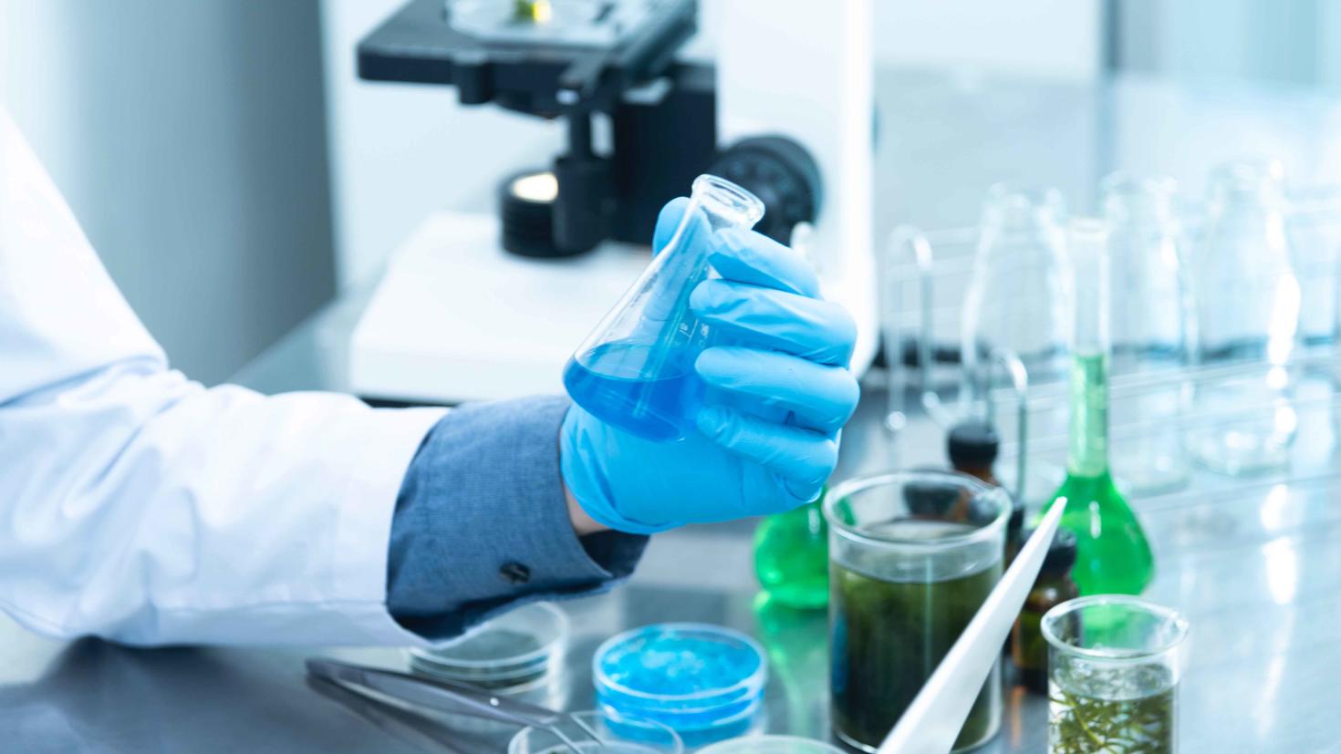 une main qui tient un bécher de laboratoire