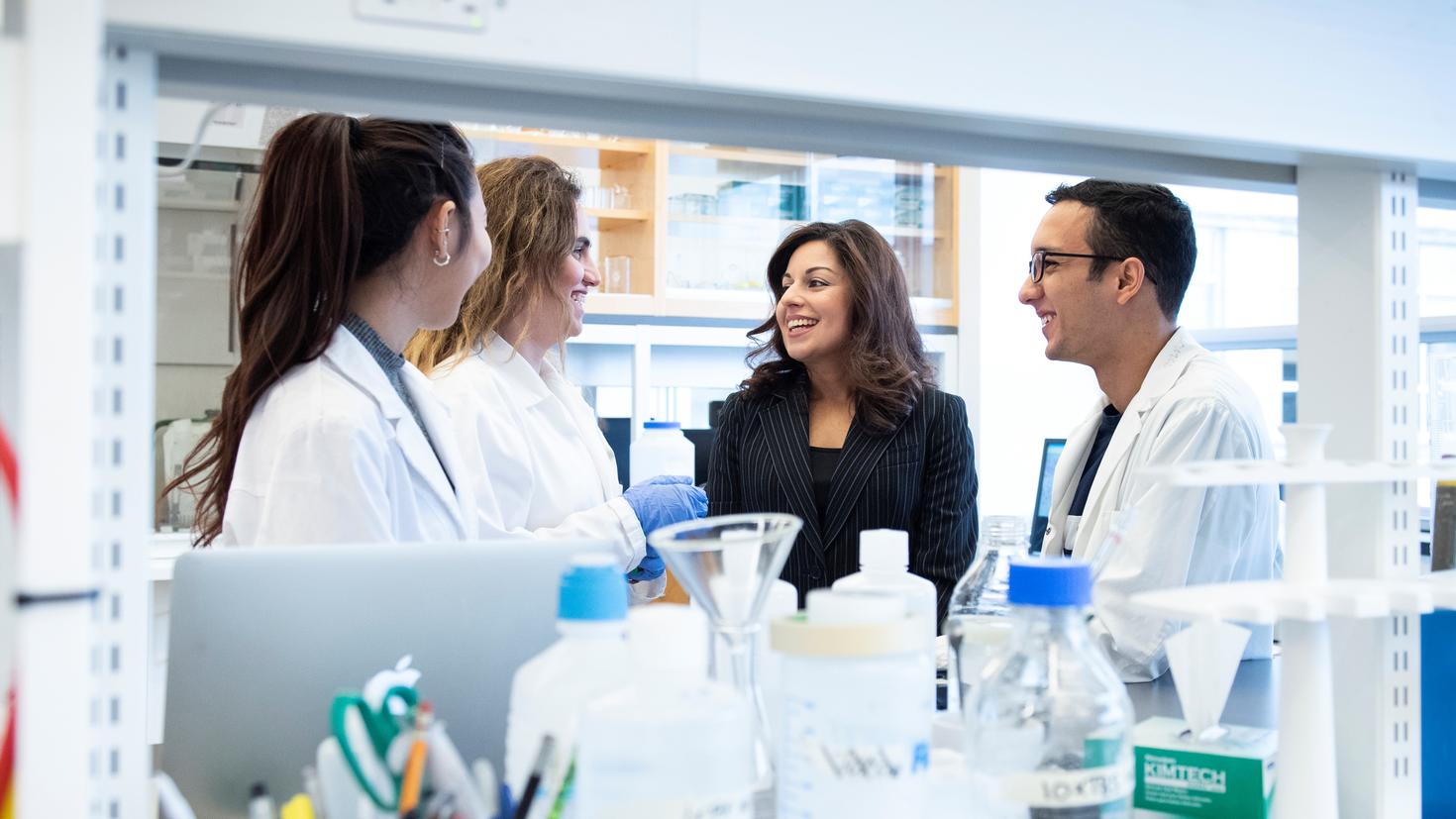 Quatre chercheurs, dont la Dre Nafissa Ismail, discutent et sourient dans un laboratoire.