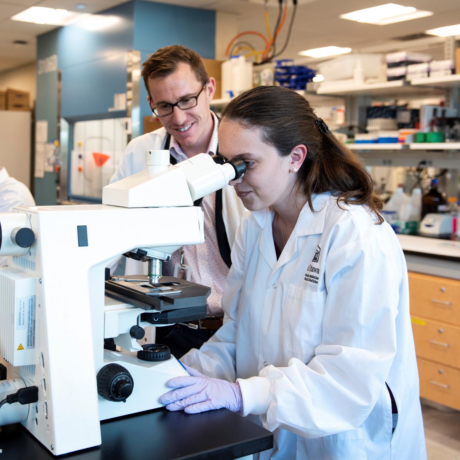 Haley Geertsma et le Dr Maxime Rousseaux utilisant un microscope.