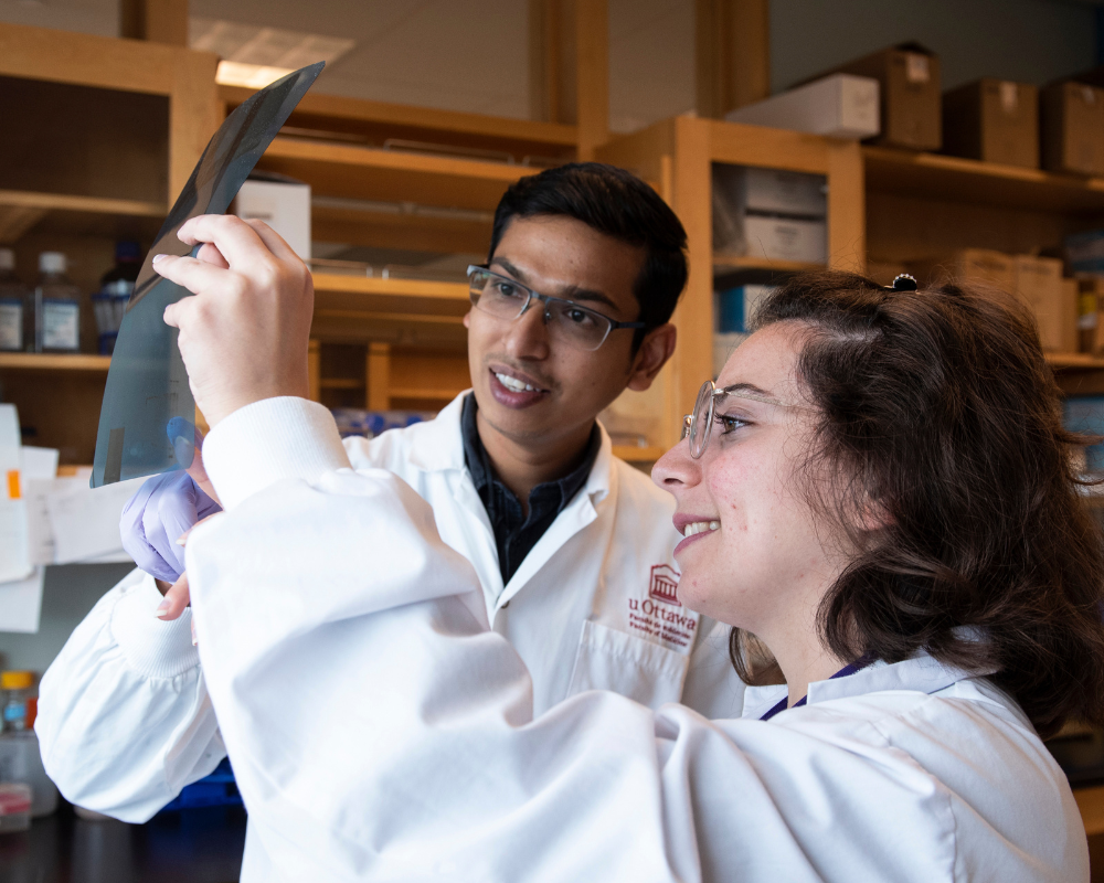 Deux stagiaires souriant et analysant un résultat de laboratoire.