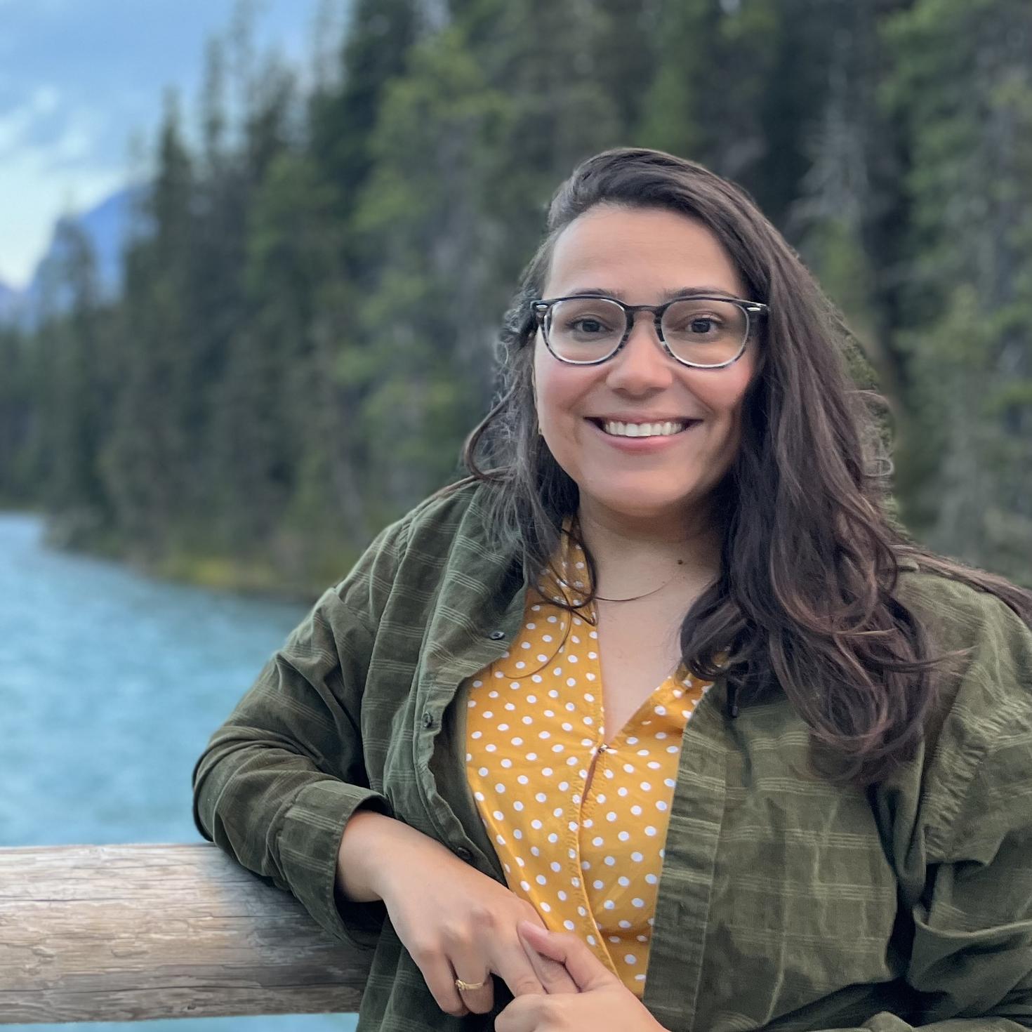 Monique Almeida souriante avec une forêt en arrière-plan.