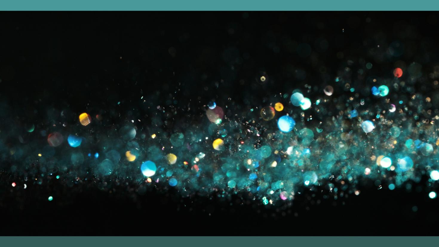 Une image abstraite de paillettes tombant sur un fond noir.