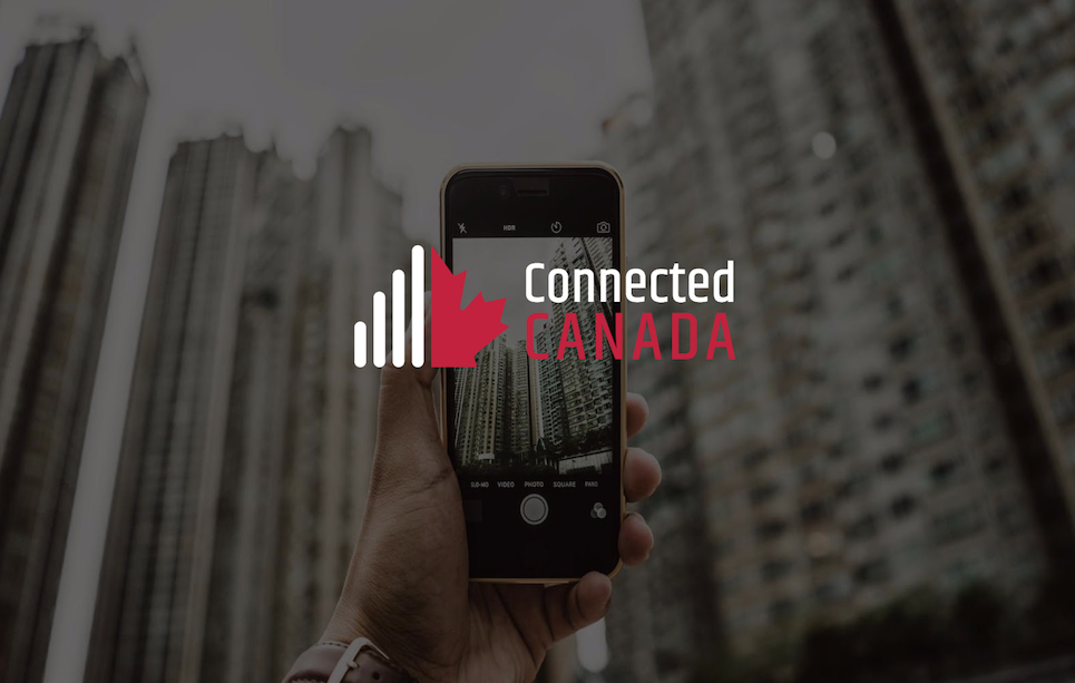 main tenant un téléphone portable en train de prendre une photo de bâtiments, avec les mots « Canada connecté » superposés.