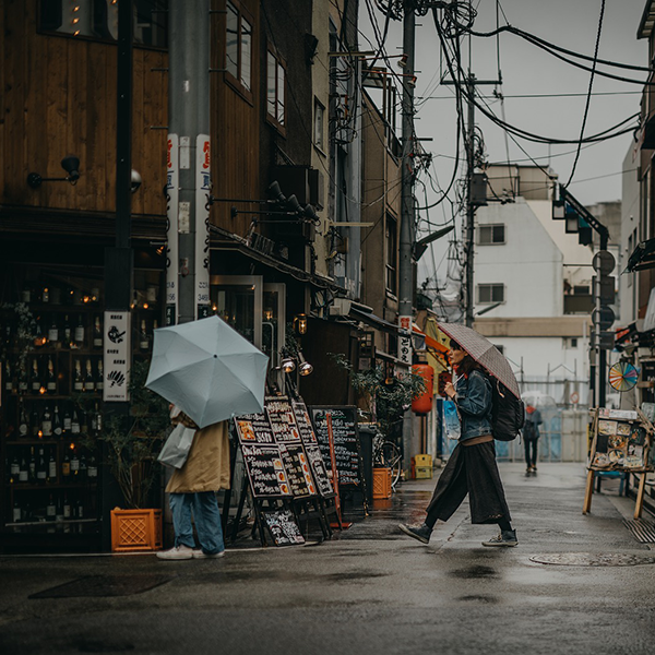 Pedestrians holding umbrellas walking down city street.