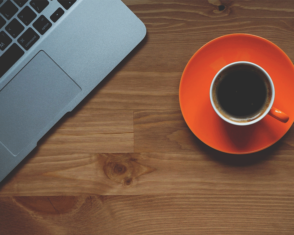 Coffee cup next to a computer.